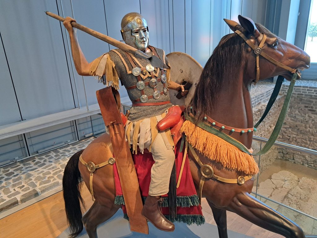 Reconstruction of a Roman cavalryman on horseback, wearing armour and carrying a spear and shield.